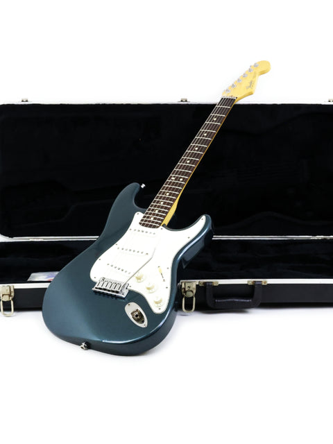 A green Fender Strat Plus Deluxe electric guitar from 1989, elegantly stored in a protective case.
