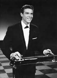 A man in a tuxedo proudly displays a 1930s Rickenbacher Electro Lap Steel guitar, merging sophistication with musical flair.