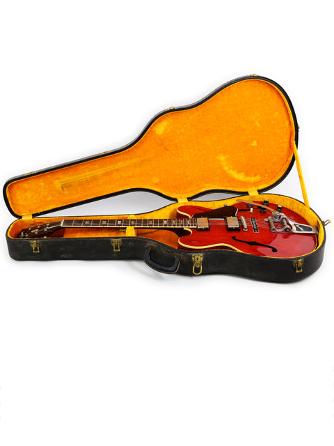 A red 1963 Gibson ES-335 guitar in its case, displayed on a white background.