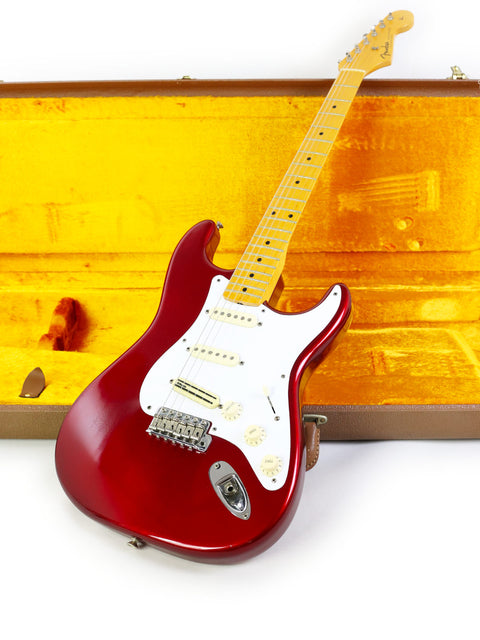 A red Fender Vintage Hot Rod ‘57 Stratocaster guitar securely placed in a yellow case, emphasizing its bold color contrast.