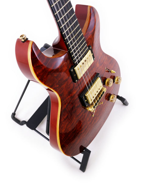 A red guitar on a black stand, labeled Jarrett Forza, Serial #00001, made in the USA in 2007.