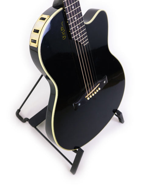 A sleek black Gibson Chet Atkins SST guitar from 1998 displayed on a stand, highlighted by a simple white background.