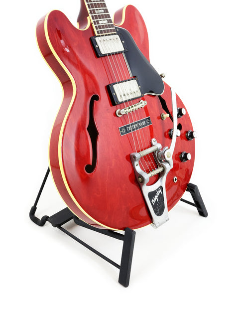 A striking red 1963 Gibson ES-335 guitar on a stand, representing vintage craftsmanship.