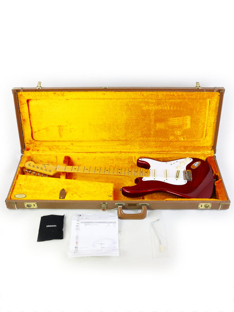 A striking red Fender Vintage Hot Rod ‘57 Stratocaster guitar nestled in a bright yellow case, highlighting its classic appeal.