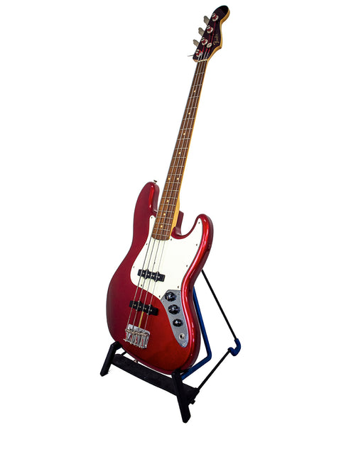 A striking red bass guitar, the Fender Custom Shop ‘62 Jazz Bass Reissue, elegantly positioned on a stand.
