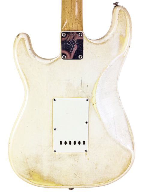 A stunning white 1968 Fender Stratocaster guitar with a wooden body and pick guard, representing vintage musical artistry.