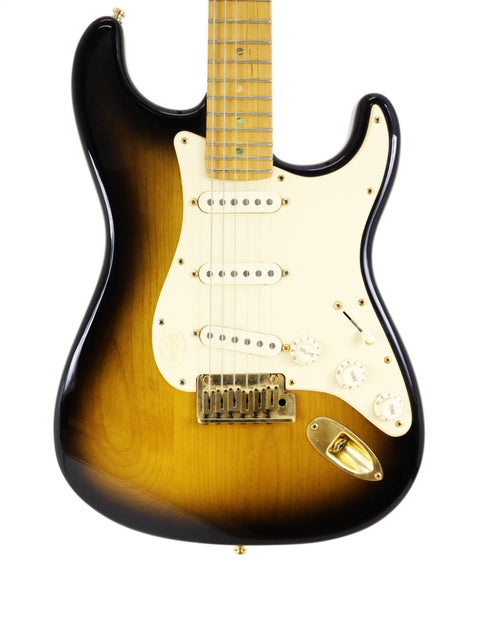 A sunburst electric guitar with a white pickguard and maple neck against a white background.