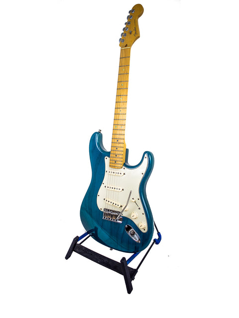 A vibrant blue Fender American Deluxe Stratocaster electric guitar resting on a stand, highlighting its classic design.