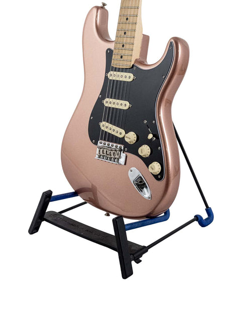 A vibrant pink guitar on a stand, showcasing a black pick guard, identified as a 2019 Fender American Performer Stratocaster.