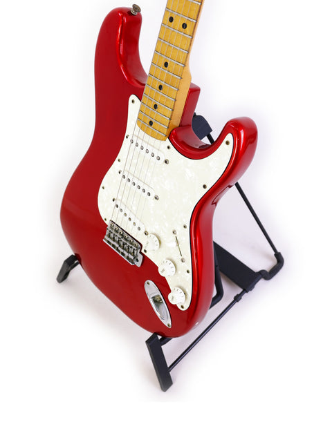 A vibrant red electric guitar, a 1979 Fender Stratocaster, displayed on a stand with a minimalist white backdrop.