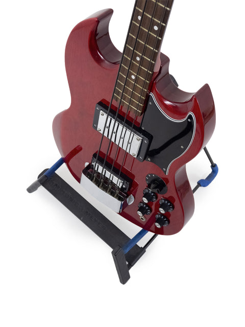 A vibrant red electric guitar displayed on a blue stand, showcasing the Ibanez 2403B Lawsuit Bass design from 1976.