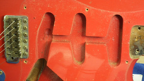 A vintage 1957 Fender Stratocaster in Dakota Red with a distinctive metal plate, showcasing its classic design.