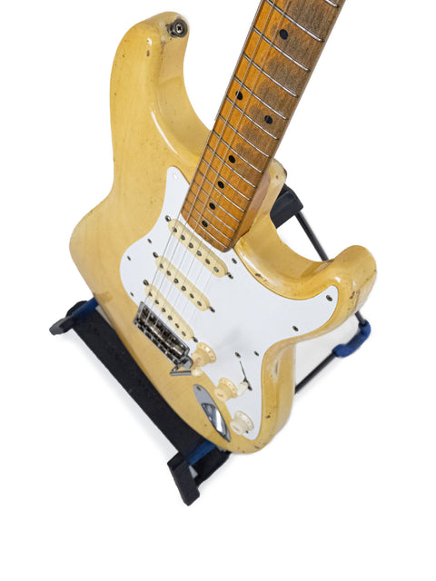 A vintage 1959 Fender Stratocaster guitar with a white body, displayed elegantly on a stand.