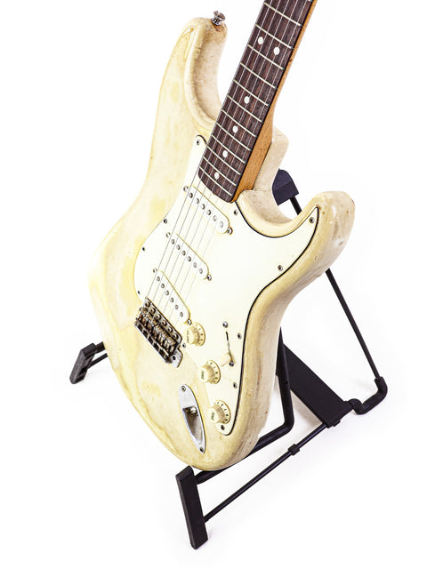 A vintage 1968 Fender Stratocaster in white, beautifully positioned on a black stand, ready to play.