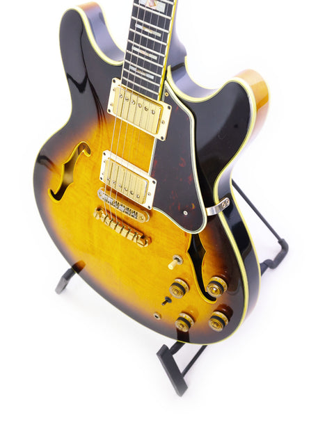 A vintage 1981 Ibanez Artist AS200 guitar with a striking sunburst finish, elegantly positioned on a stand.