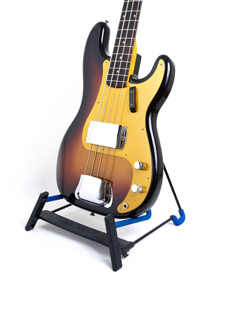 A vintage Fender Precision Bass guitar displayed on a blue stand, highlighting its iconic style from the USA, 1958/59.