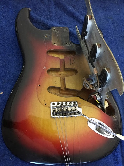 A vintage Fiesta Red 1964 Fender L Series Stratocaster with a broken neck and bridge, highlighting its wear.