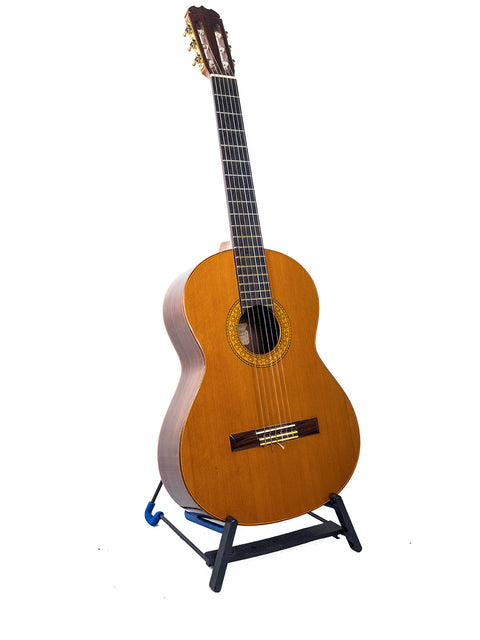 A vintage K Yairi YC90 Concert Classical Guitar from Japan, elegantly positioned on a stand with a white backdrop.