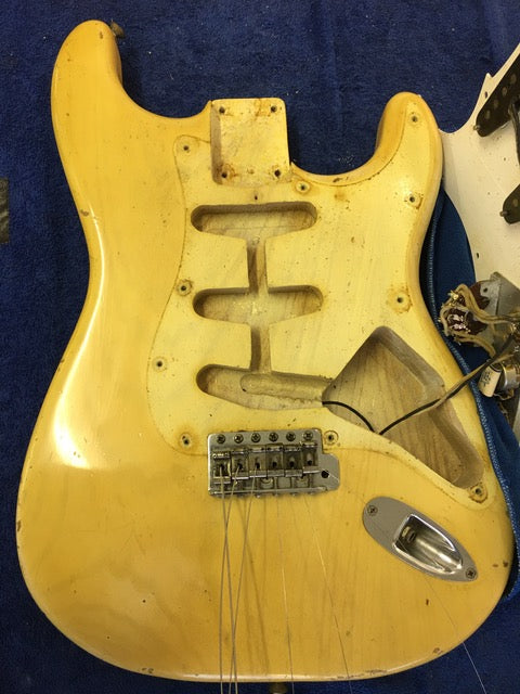 A vintage blond Fender Stratocaster from 1959, displaying a broken neck and bridge, symbolizing its storied past.