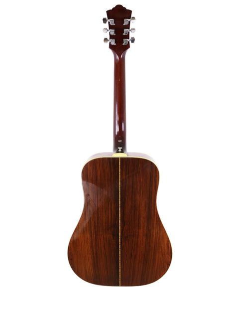 A wooden 1974 Guild D-50 Bluegrass Special guitar prominently featured with a white background.