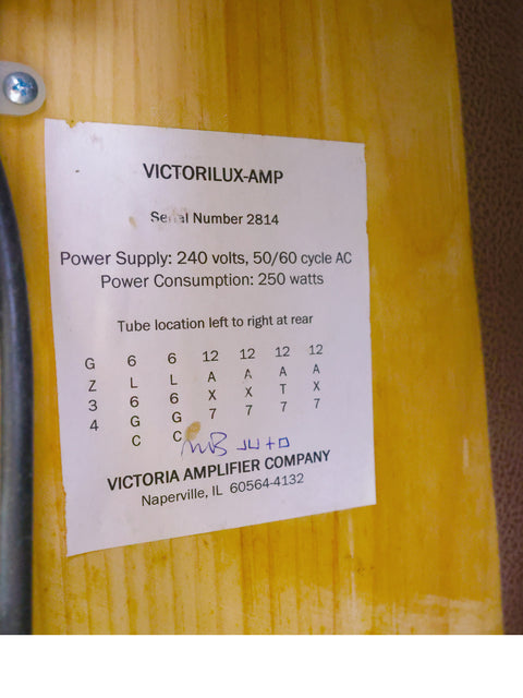 A wooden table displays a sign reading "victorolus amp," referencing the Victoria Victorilux 3x10 Combo Amplifier from 2005.