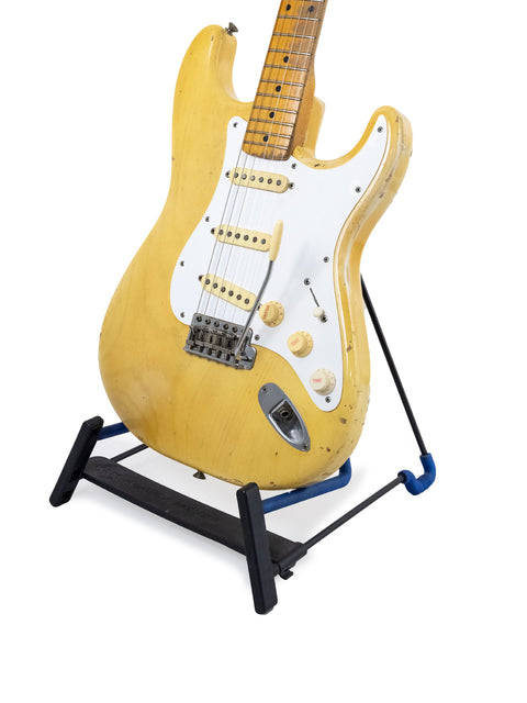A yellow 1959 Fender Stratocaster guitar with a maple neck, elegantly positioned on a black stand.