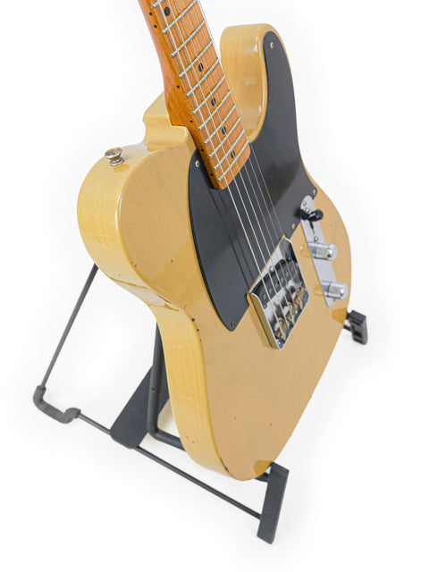 A yellow Fender Master Built Jason Smith Esquire guitar on a stand, featuring a sleek black body, USA 2018 model.