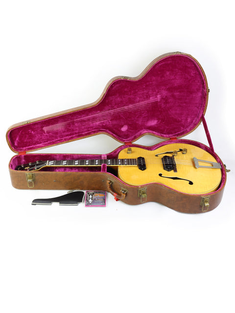 A yellow Gibson ES-300 guitar from 1952, elegantly stored in a pink case, emphasizing its vintage appeal.
