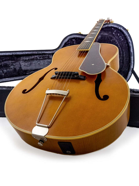 An Epiphone Masterbilt De Luxe F-Hole Archtop guitar from 2016 displayed in its case on a clean white backdrop.