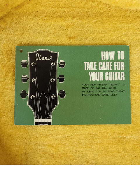 An instructional book on guitar care beside a vintage 1976 Ibanez 2403B Lawsuit Bass guitar.