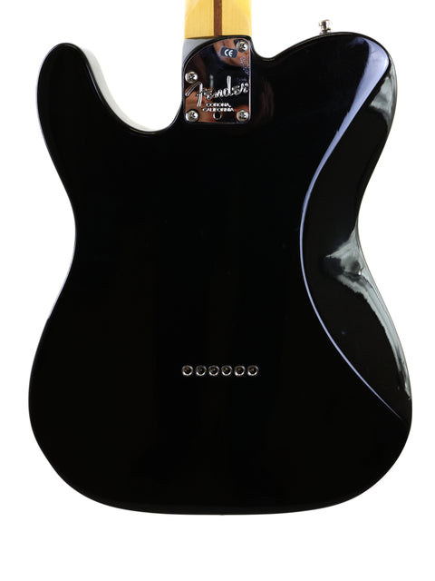 Black Fender American Deluxe Telecaster guitar featuring a striking white pickguard, highlighting its classic style.
