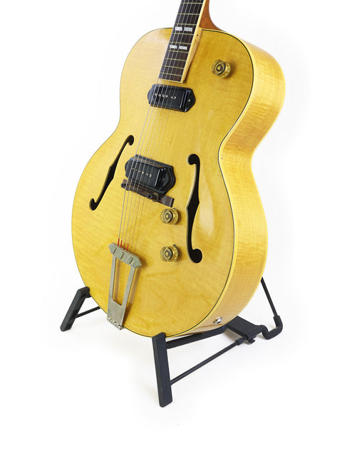Classic 1952 Gibson ES-300 guitar on a stand, highlighted by a stark white background for a timeless look.