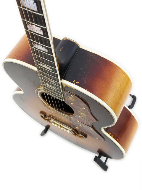 Classic 1954 Vintage Gibson J-200 guitar with a wooden body, beautifully positioned on a wooden stand.
