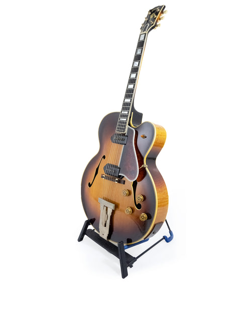 Classic 1955 Gibson L-5 CES guitar resting on a stand, highlighted by a simple white background.