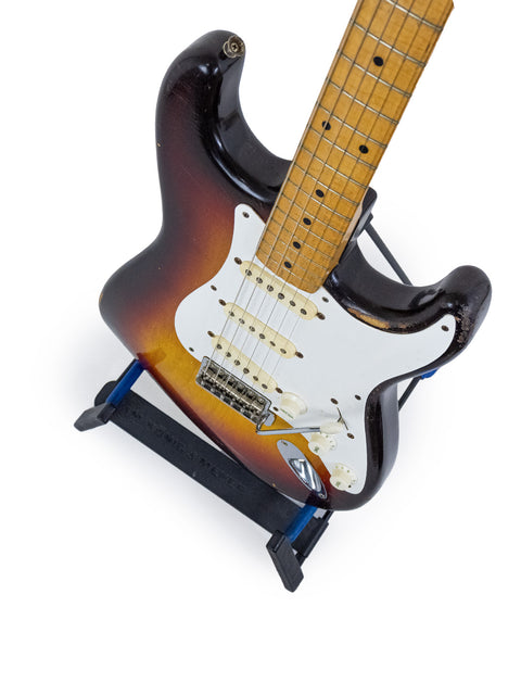Classic 1958 Fender Stratocaster guitar resting on a stand, set against a white background.