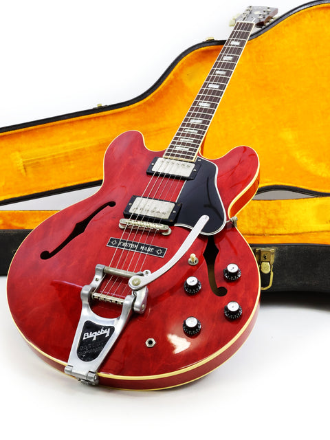 Classic red Gibson ES-335 guitar from 1963, resting in its case on a pristine white backdrop.