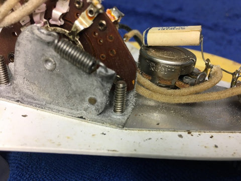 Close-up image of a 1959 Fender Stratocaster's electronic device, highlighting intricate wires and screws on a vintage model.
