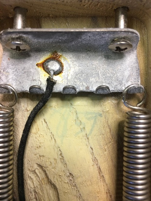 Close-up image of a metal box with a spring and wire, integral to the vintage 1959 Fender Stratocaster guitar.