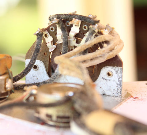 Close-up image of a small electrical device, highlighting the vintage 1957 Fender Stratocaster with Dakota Red refinishing.