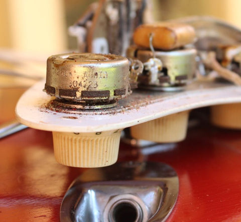 Close-up image of a vintage 1957 Fender Stratocaster, Dakota Red finish, highlighting its metal cover.