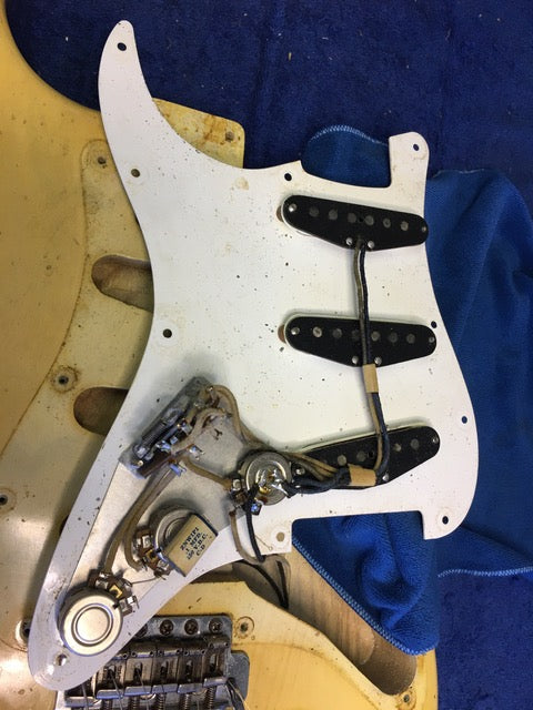 Close-up of a 1959 Fender Stratocaster neck in blond maple, with a few screws absent, reflecting its vintage character.