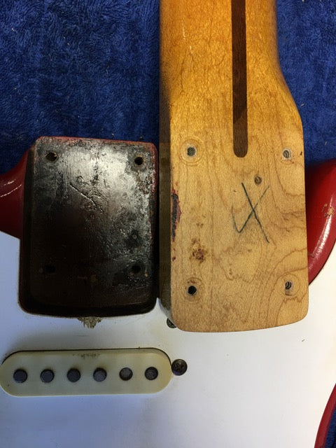Close-up of a vintage 1957 Fender Stratocaster neck, showcasing its Dakota Red finish and intricate details.