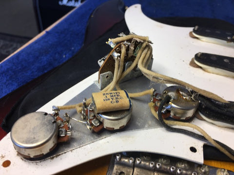 Close-up of a vintage 1958 Fender Stratocaster guitar, displaying wires and pickups that enhance its iconic sound.