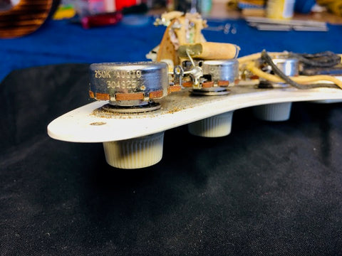 Close-up of a vintage 1958 Fender Stratocaster guitar, showcasing a white pickguard and assorted parts in detail.