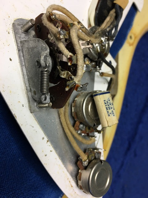 Close-up of a vintage 1959 Fender Stratocaster, focusing on the blond wood and detailed wiring components.