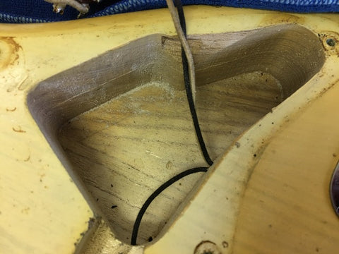 Close-up of a vintage 1959 Fender Stratocaster guitar featuring a hole in the maple neck, showcasing its unique character.