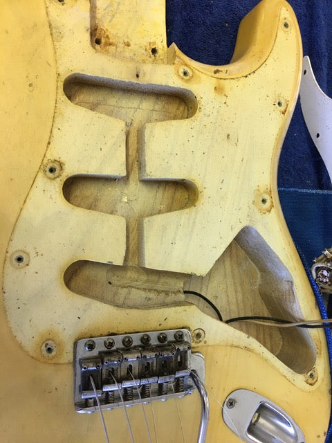 Close-up of a vintage 1959 Fender Stratocaster with a broken neck, showcasing its blond finish and maple neck details.