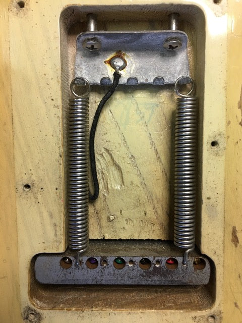 Close-up of a vintage metal box with springs, showcasing intricate details of a 1959 Fender Stratocaster's components.
