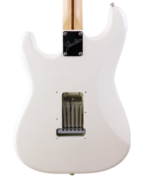 Close-up of a white Fender electric guitar's body with six tuning pegs visible.