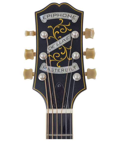 Close-up of an acoustic guitar headstock labeled "the phoenix," showcasing the Epiphone Masterbilt De Luxe F-Hole design.